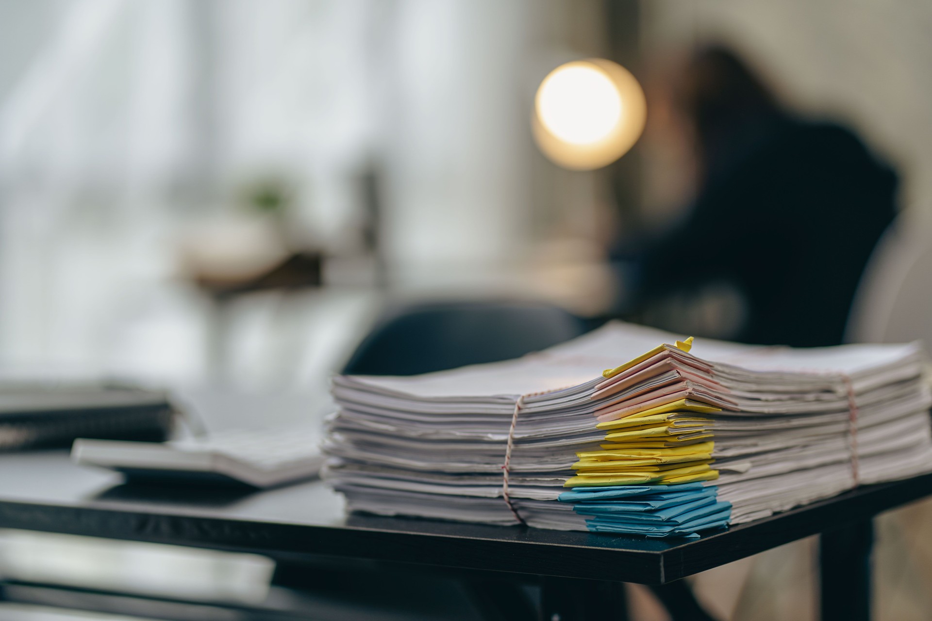 a pile of papers lying on the business desk in the office Archived documents with paper clips on the table. The unfinished information is in the building near the window. business idea